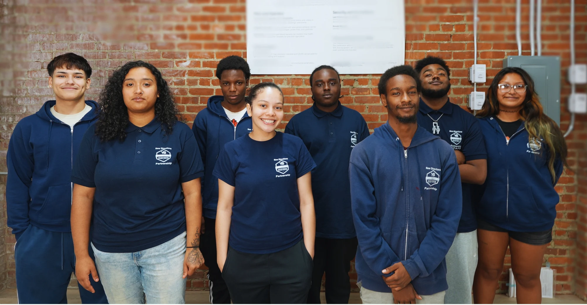YouthBuild participants standing together in front of a brick wall